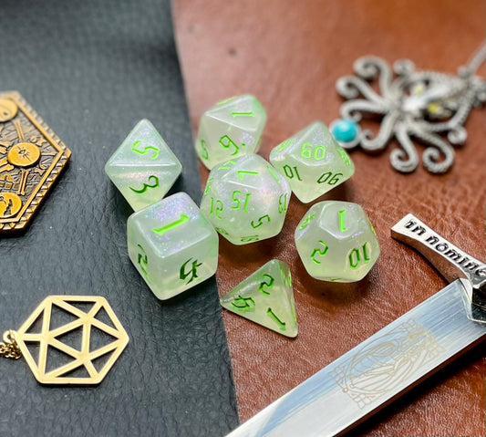 Glitter Shimmer With Green Font Polyhedral Dice Set  Traverse the galaxy with these unique dice. Combining frosted resin with shimmer and green font.  They are standard 16mm polyhedral dice sets perfect for Tabletop games and RPG's such as pathfinder or dungeons and dragons.  This set includes one of each D20, D12, D10, D%, D8, D6, D4.