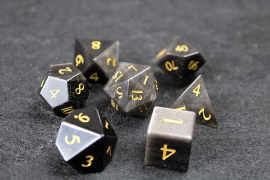 Natural Silver Obsidian Gemstone Dice Set
Polished silver flecked Obsidian gemstone with gold numbers dice set
Roll in style with these polyhedral dice sets perfect for Tabletop games and RPG's such as pathfinder or dungeons and dragons.
This set includes one of each D20, D12, D10, D%, D8, D6, D4.
Available both with or without a PU leather dice storage box.