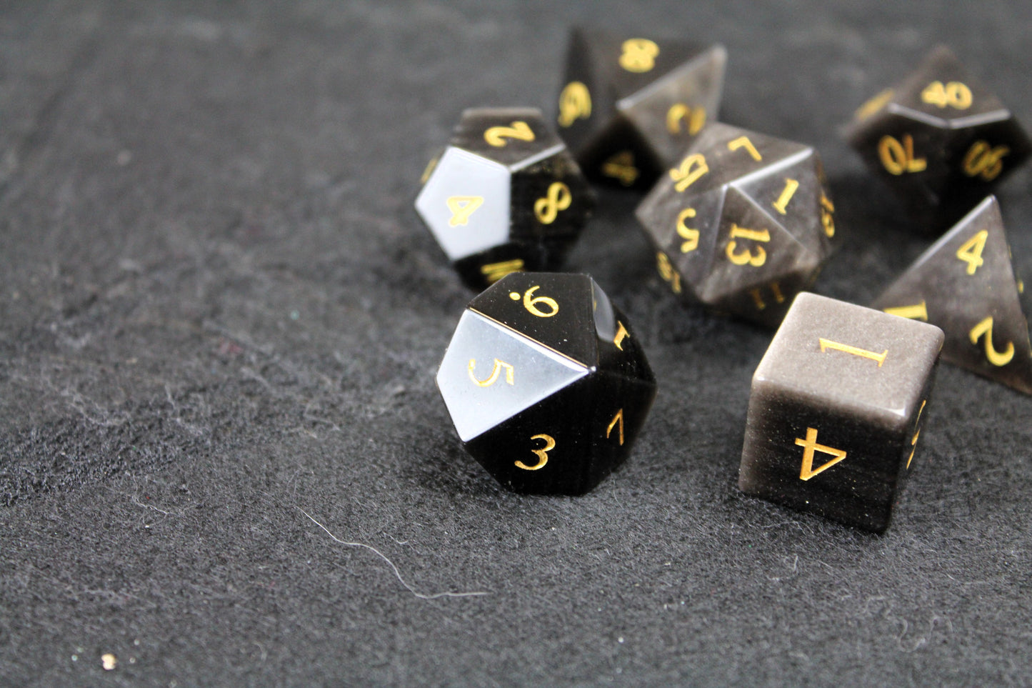 Natural Silver Obsidian Gemstone Dice Set
Polished silver flecked Obsidian gemstone with gold numbers dice set
Roll in style with these polyhedral dice sets perfect for Tabletop games and RPG's such as pathfinder or dungeons and dragons.
This set includes one of each D20, D12, D10, D%, D8, D6, D4.
Available both with or without a PU leather dice storage box.
