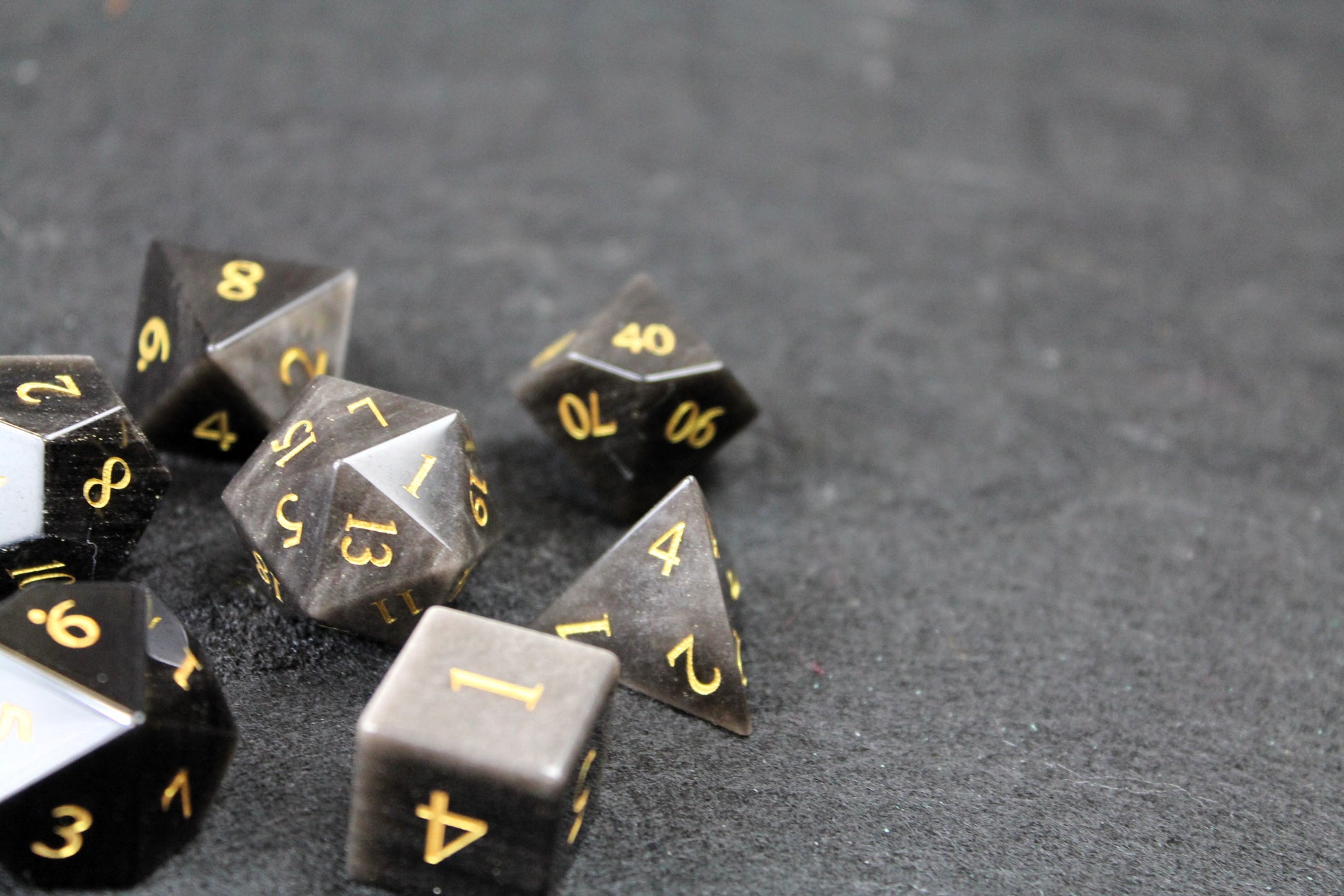 Natural Silver Obsidian Gemstone Dice Set
Polished silver flecked Obsidian gemstone with gold numbers dice set
Roll in style with these polyhedral dice sets perfect for Tabletop games and RPG's such as pathfinder or dungeons and dragons.
This set includes one of each D20, D12, D10, D%, D8, D6, D4.
Available both with or without a PU leather dice storage box.