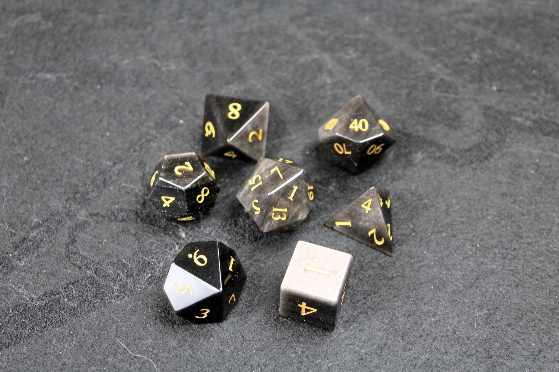 Natural Silver Obsidian Gemstone Dice Set
Polished silver flecked Obsidian gemstone with gold numbers dice set
Roll in style with these polyhedral dice sets perfect for Tabletop games and RPG's such as pathfinder or dungeons and dragons.
This set includes one of each D20, D12, D10, D%, D8, D6, D4.
Available both with or without a PU leather dice storage box.