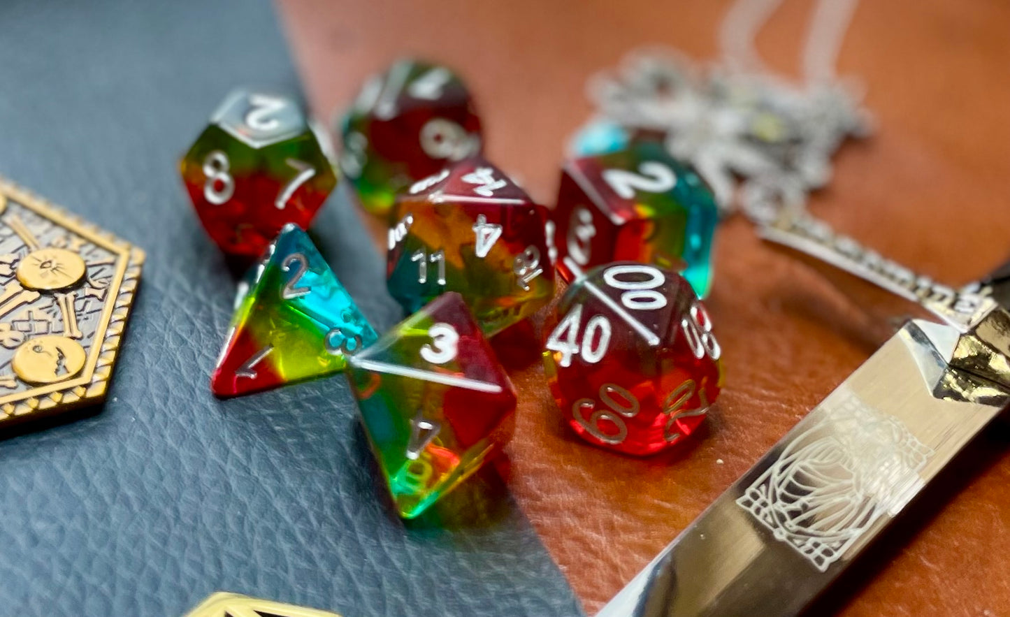 Pride glitter resin polyhedral dice set. Yet another reason to add to your growing dice collection with these fantastic resin dice. These are beautiful translucent dice featuring a range of reds, yellows and blues with gold glitter running throughout. They are standard 16mm polyhedral dice sets perfect for Tabletop games and RPG's such as pathfinder or dungeons and dragons. This set includes one of each D20, D12, D10, D%, D8, D6, D4.