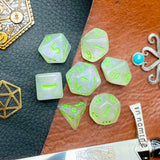 Glitter Shimmer With Green Font Polyhedral Dice Set  Traverse the galaxy with these unique dice. Combining frosted resin with shimmer and green font.  They are standard 16mm polyhedral dice sets perfect for Tabletop games and RPG's such as pathfinder or dungeons and dragons.  This set includes one of each D20, D12, D10, D%, D8, D6, D4.