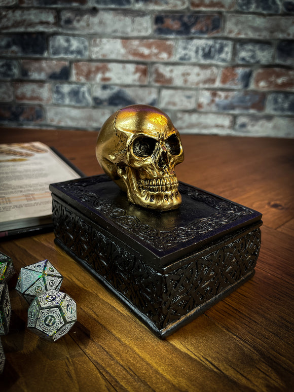 This expertly crafted box will bring macabre opulence to any room! Sat on a large black box, covered in Celtic patterns, is a small golden skull, simple yet strikingly stylish. Lift the skull upwards to reveal the perfect place to store all of your treasure. Free UK Delivery by Fandomonium