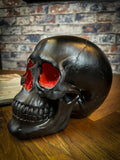 The most unassuming facade can hide the most scintillating interior. This matte black skull has eyes and nose holes that open up to a sparkling red world. A large crack at the side of the skull reveals an enchanting red crystal geode within, sparkling in the light. Free UK Delivery by Fandomonium