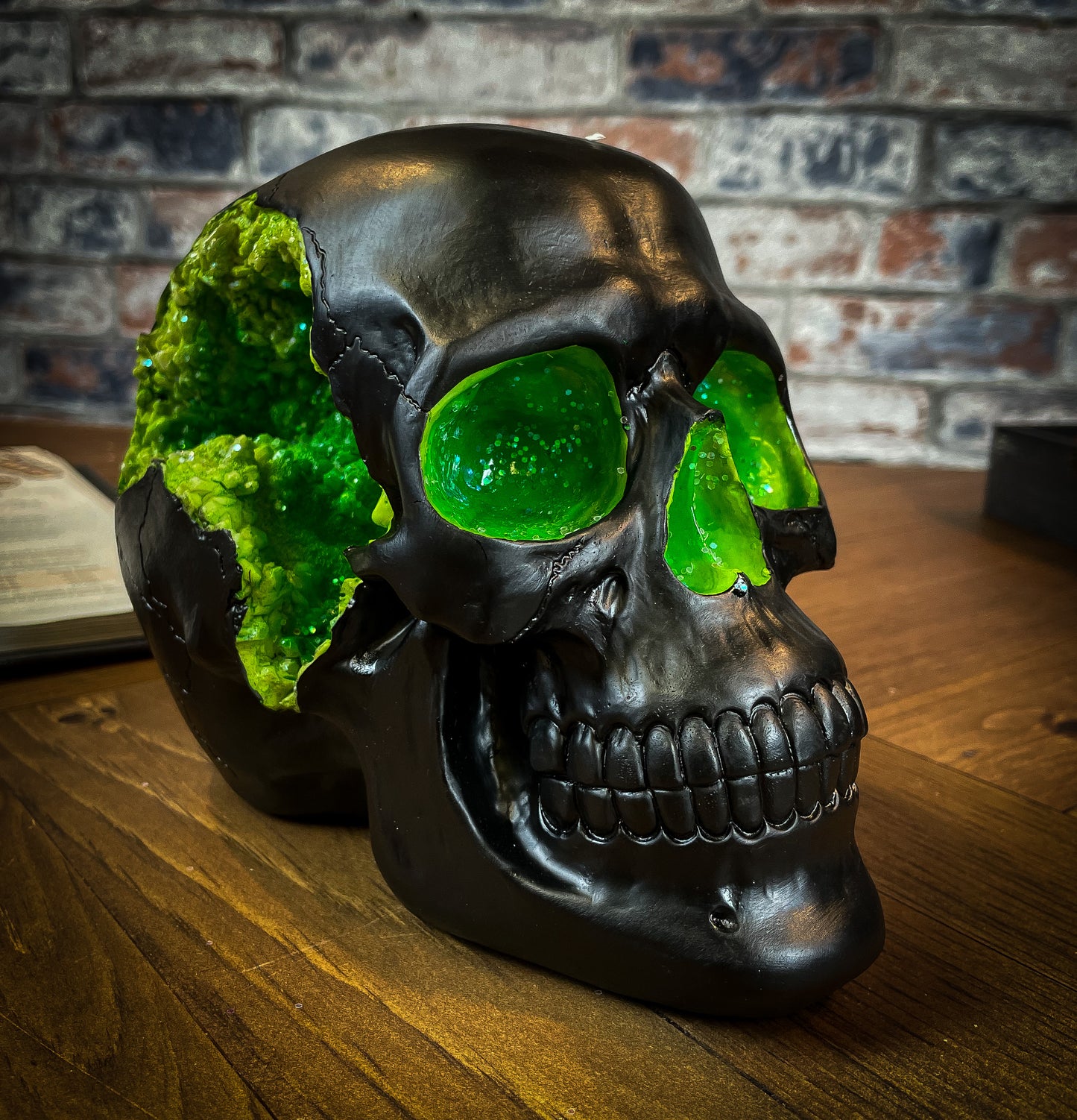 The most unassuming facade can hide the most scintillating interior. This matte black skull has eyes and nose holes that open up to a sparkling green world. A large crack at the side of the skull reveals an enchanting green crystal geode within, sparkling in the light. Free UK Delivery by Fandomonium