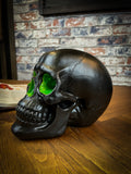 The most unassuming facade can hide the most scintillating interior. This matte black skull has eyes and nose holes that open up to a sparkling green world. A large crack at the side of the skull reveals an enchanting green crystal geode within, sparkling in the light. Free UK Delivery by Fandomonium