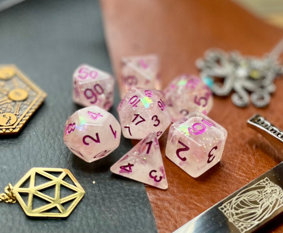 Glitter Shimmer With Pink Font Polyhedral Dice Set  Traverse the galaxy with these unique dice. Combining frosted resin with shimmer and pink font.  They are standard 16mm polyhedral dice sets perfect for Tabletop games and RPG's such as pathfinder or dungeons and dragons.  This set includes one of each D20, D12, D10, D%, D8, D6, D4.