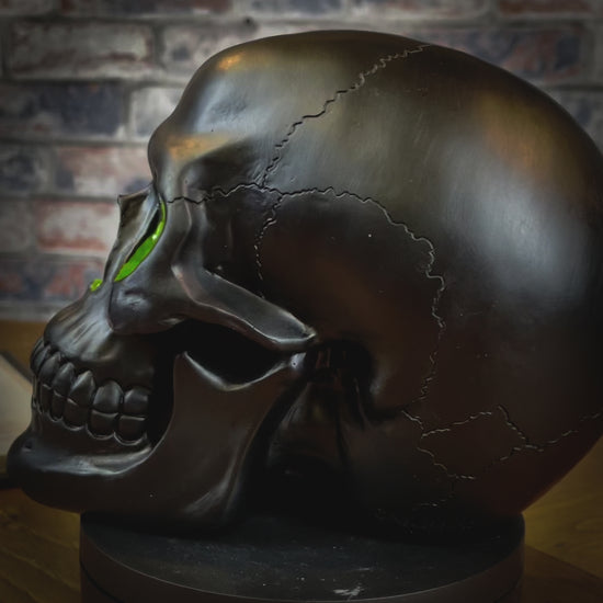 The most unassuming facade can hide the most scintillating interior. This matte black skull has eyes and nose holes that open up to a sparkling green world. A large crack at the side of the skull reveals an enchanting green crystal geode within, sparkling in the light. Free UK Delivery by Fandomonium