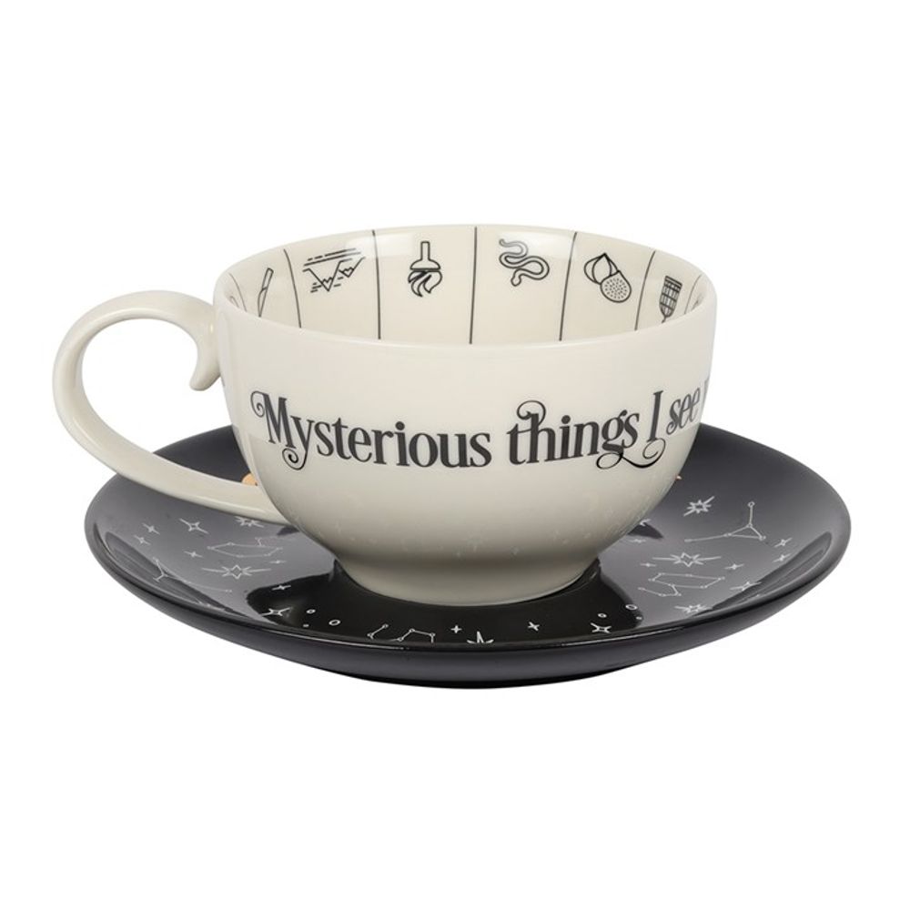 Fortune Telling Ceramic Teacup  A stunning and unique tea cup to be used for reading tea leaves. Features a variety of fortune telling and astrological symbols accented by gold foil, a contrasting black saucer, and mystical 'Mysterious things I see when telling fortunes in tea' text. Truly a piece to be treasured. By Fandomonium