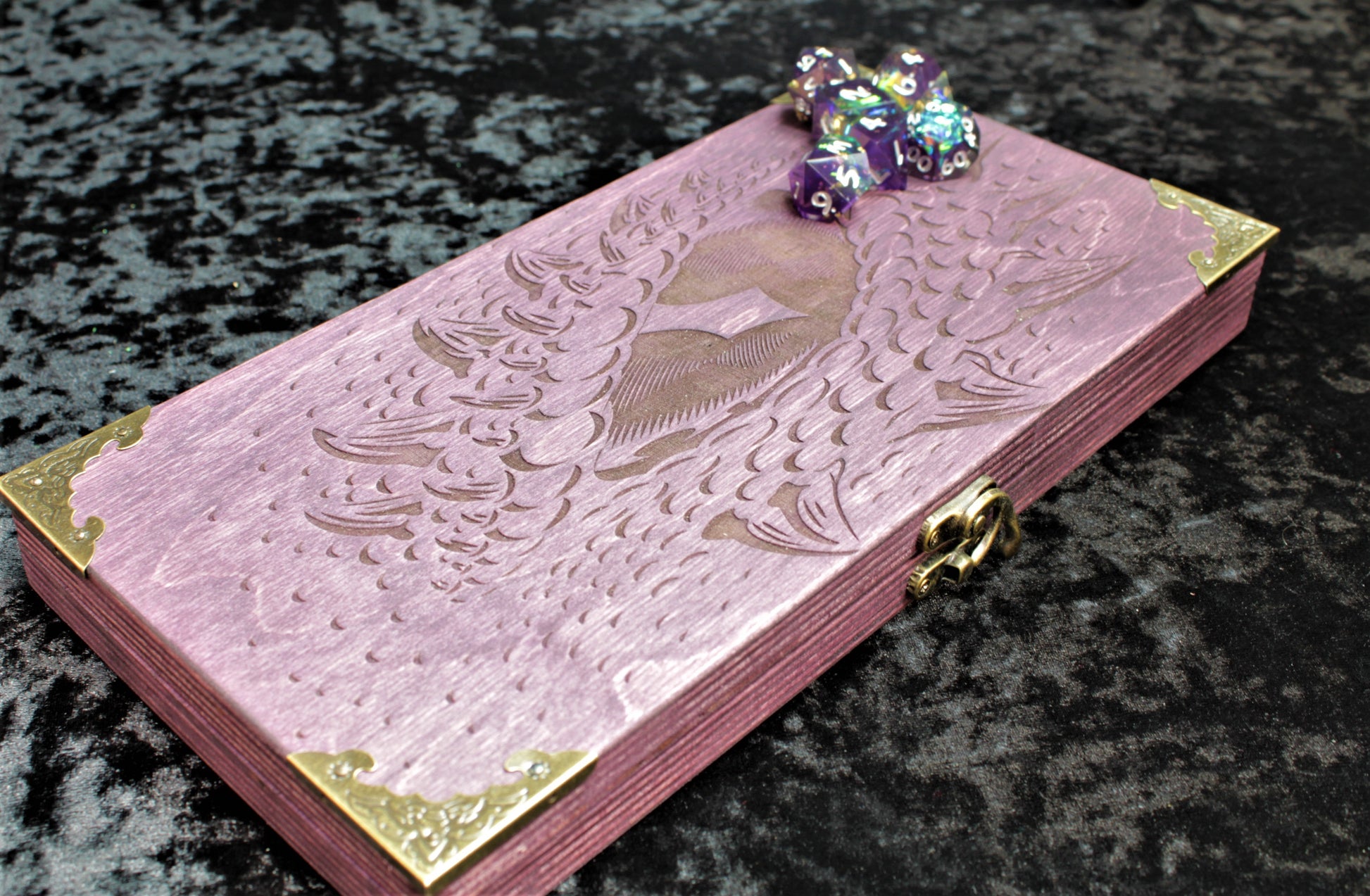 Dragon Eye Dice Box, Accessory Storage and Roll Tray.

Hand finished dice box for storing dice, cards, counters and accessories with handy pen storage and in built roll tray. Choose from 8 vibrant colour finished to make your box unique to you. Complete with our unique dragon's eye design, metal corner protectors and clasp